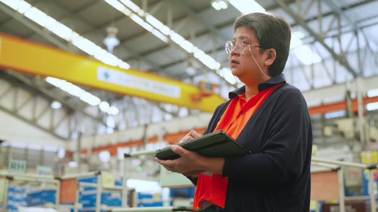 Senior production engineer using tablet and working in the factory. She checked the facility overall items of production line and quantity before sent them to server for collect data in the next  in the plastic industry factory.