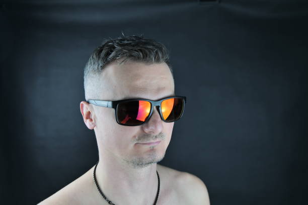 istock A young white man with reflective, red sun glasses is posing in the camera at a studio photo shoot. 1460526875