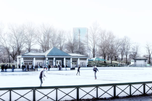 Ice skaters at the outdoor winter ice skating ring on the Boston Common Frog Pond. Motion blur.