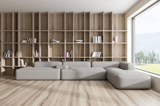istock Stylish relaxing interior with couch and wooden shelf, panoramic window 1460528311