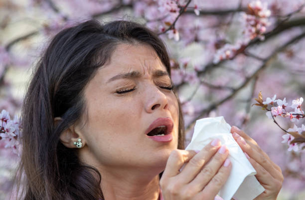 istock Girl sneezing in front of blooming tree in spring 1460528535