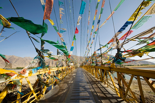 Tibetan prayer flags fluttering off a bridge \nnear Lhasa, Tibet