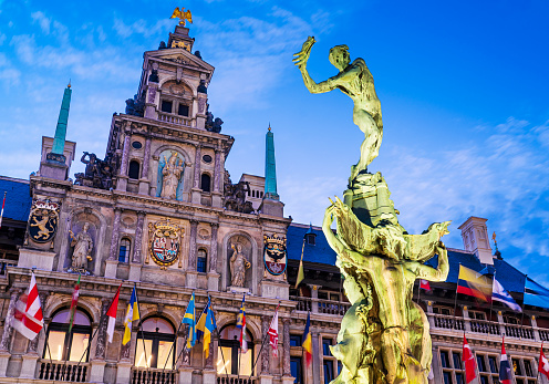 The historic Grote Markt and Brabo's Monument lit up in early evening. Brabo's statue was installed in 1887 and the Stadhuis (Town Hall building) was built in 1565.