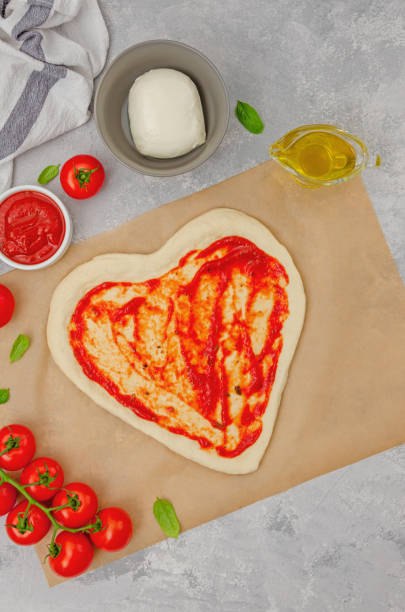 istock Pizza Margherita shaped heart with cherry tomatoes, mozzarella and basil on a gray concrete background. Food concept for Valentine's Day. Copy space. 1460531131