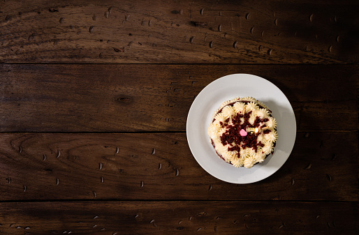 High angle view of delicious gourmet birthday cake on white plate over a rustic pine wood table.