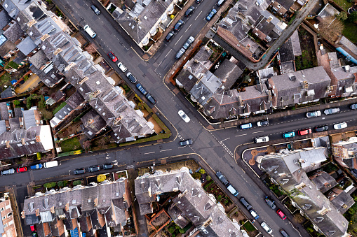 An aerial view directly above of the rooftops of back to back terraced houses with the connecting roads and junctions of a suburban neghbourhood in England
