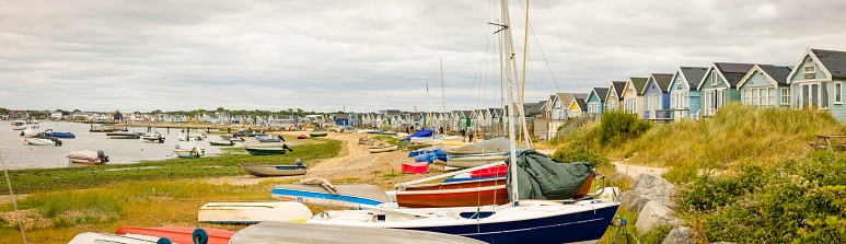 Dorset, UK - July 07, 2022. Rows of boats and beach huts at the seaside. Panoramic view of Hengistbury Head and Christchurch Harbour