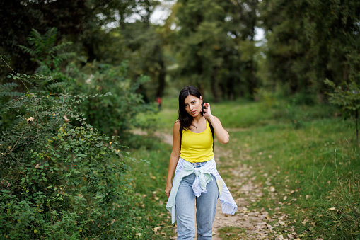 Relaxed young woman walking in green nature on sunny day