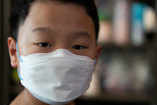 kid in childhood wear mask looking at camera indoors