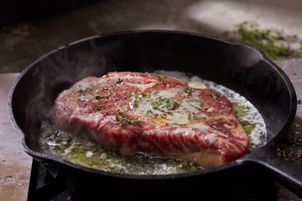Pan Searing Beef Eye Rib Steak Pan Searing Beef Eye Rib Steak with Garlic, Butter and Thyme steak stock pictures, royalty-free photos & images