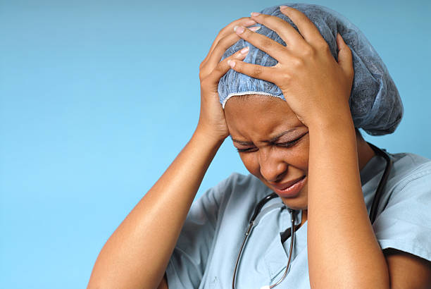 Nurse with her hands on her head signaling stress stock photo