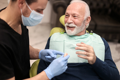 Senior man at a dentist's office, looking at dentures. About 65 years old, Caucasian male.