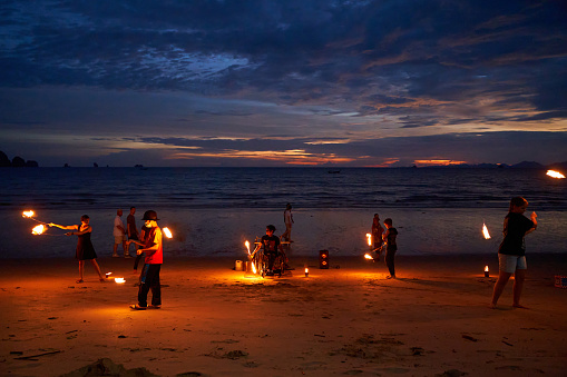 street performers put on a fire show for tourists on the beach after sunset. Thailand, Krabi - 10.12.2022