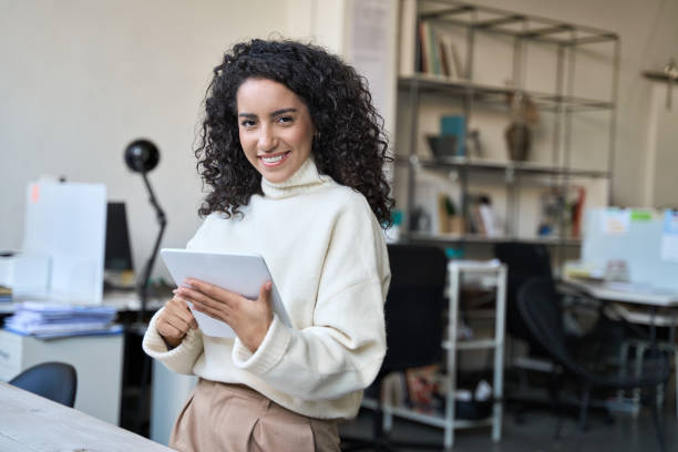 istock Smiling latin young professional business woman using digital tablet in office. 1460548400
