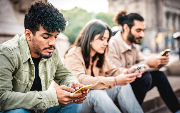 Urban people group using mobile smart phone sitting at university college yard - Young friends addicted by smartphone tech devices - Technology concept with always connected students on desat filter stock photo