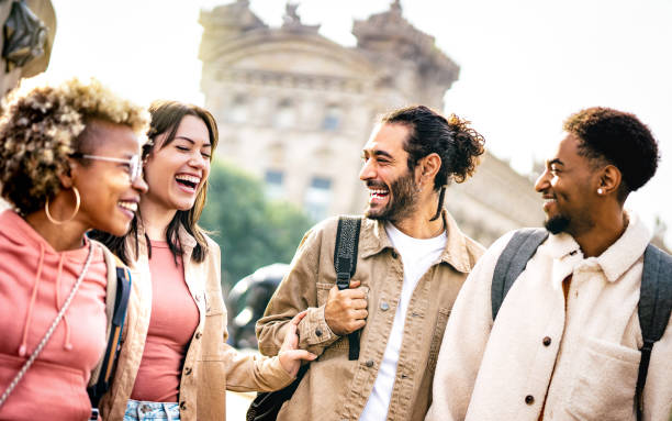 Multi cultural happy best friends talking and having fun at Barcelona city center - Friendship life style concept on young genz people meeting out side at college campus yard - Bright backlight filter stock photo