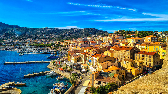 Calvi historic city center with sandy beach, historic houses and harbor with boats and yachts, Corsica, France, Europe.