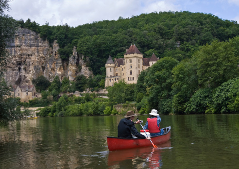 Young people canoing on the Dordogne River in France, past medieval castles and striking ancient cliffs.  The lad in the back of the canoe holds a small camera.  The couple in the canoe are my son and my wife, who would be excited to see their photo in use.  I would appreciate it if anyone using this photo could pm me to say where it is used.  Thanks