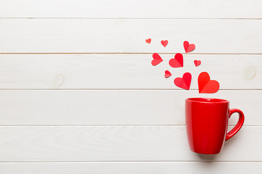 red cup on colored background, splashes of red little hearts, top view with copy space.