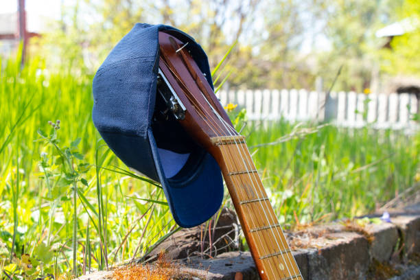 casquette bleue de baseball accrochée à une vieille guitare sur fond d’herbe verte - baseball cap baseballs male old photos et images de collection