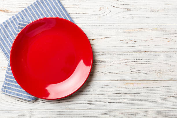 istock Top view on colored background empty round red plate on tablecloth for food. Empty dish on napkin with space for your design 1460557049