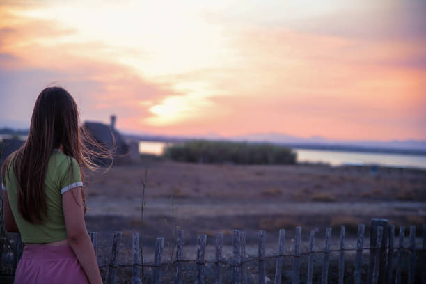 Female Teenager looking at sunset over the lake water in distance. Copy space