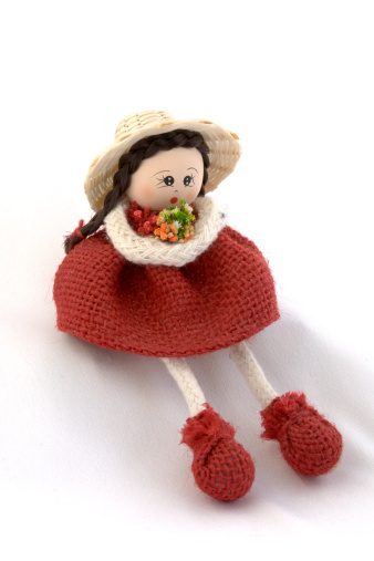 This is a Colombian-style doll of a hispanic girl, sitting and holding a bouquet of flowers. It is about 3 inches tall. The legs and arms are made or rope. The miniature flowers are made of cloth in great details.
