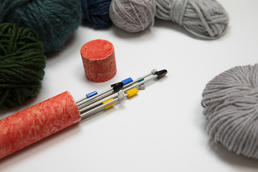 Knitting background. Set of Knitting needles, bunch of yarn in grey, green and blue colors. Wool balls on white background, retro style knitting set. Hobby, winter time leisure activities.