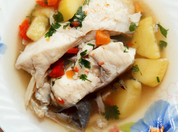 Traditional savory fish soup served hot on a plate for lunch with plenty of fish meat stock photo