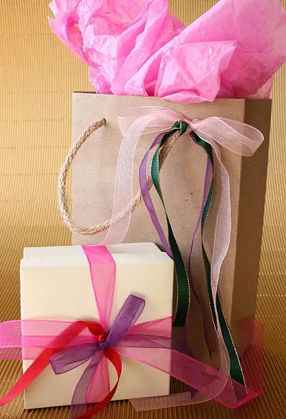 Cream colored gift box and brown gift bag with ribbons
