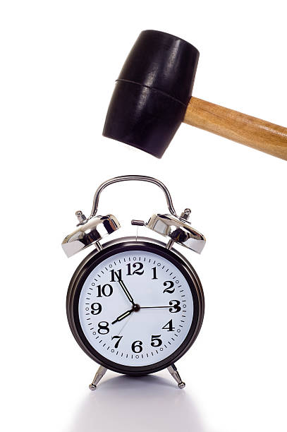 Killing Time a hand holding a black mallet or hammer about to crush an old fashioned alarm clock on a white background, time concept smash alarm clock stock pictures, royalty-free photos & images