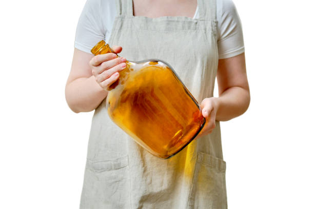 A woman holds a large bottle vase in her hands while standing on a home kitchen, close-up, isolated on a white background