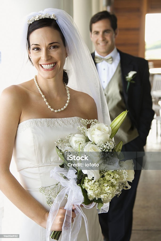 Portrait of bride and groom. Caucasian young adult bride and groom standing on porch looking at viewer and smiling. 30-34 Years Stock Photo