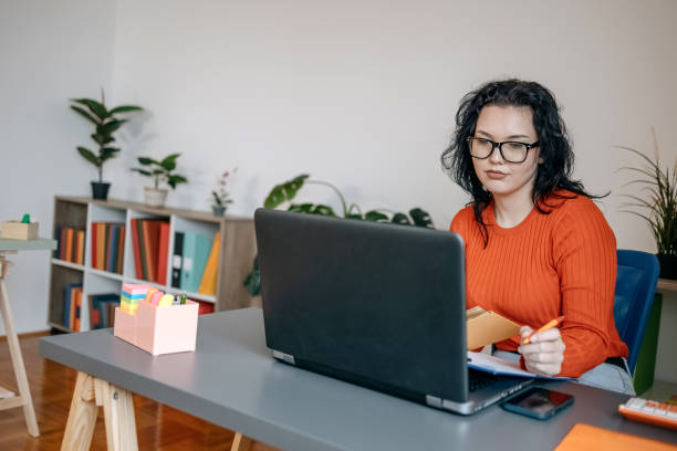 istock Young woman working in a small office using laptop and digital tablet 1460569334
