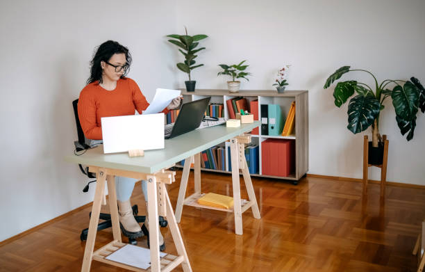 istock Young woman working in a small office using laptop and digital tablet 1460569732