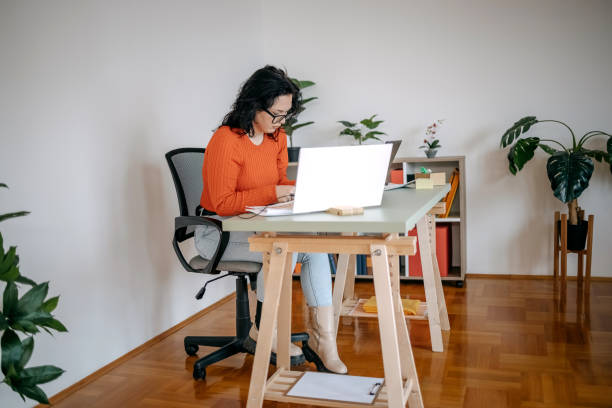 istock Young woman working in a small office using laptop and digital tablet 1460569784