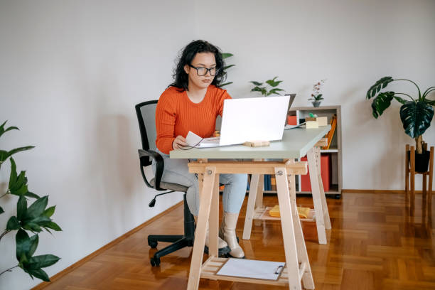 istock Young woman working in a small office using laptop and digital tablet 1460569786