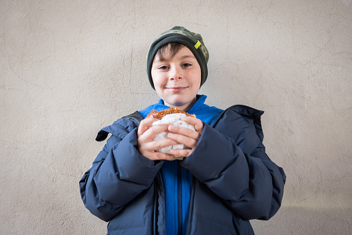 Young boy eating an hamburger front of street wall