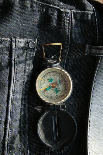 Searching concept - retro compass in a jeans pocket. Vintage compass on jeans