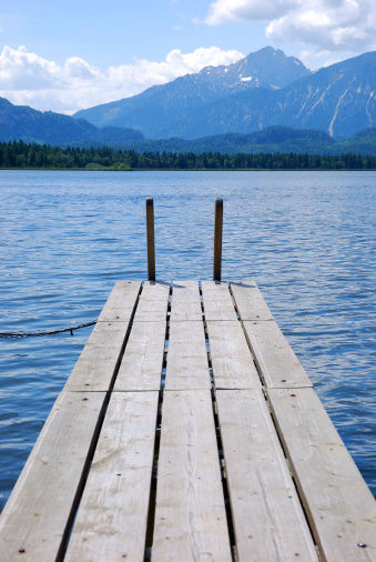 A small wooden boardwalk at Lake Hopfen (Allgaeu) with mountainview.