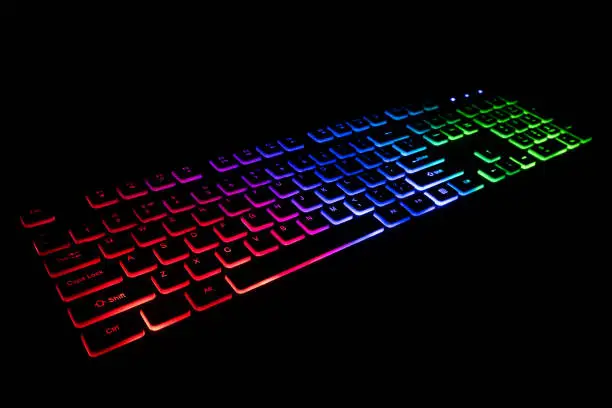 Photo of Game keyboard with color RGB backlight on black background.