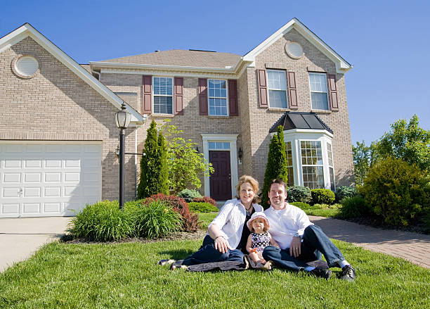 Happy Family In Front Of Their New House.