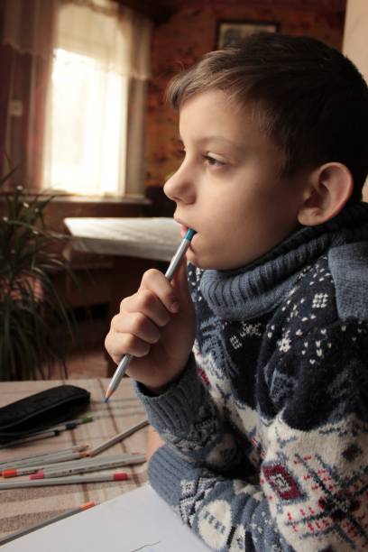 istock a boy in a Christmas sweater sits at the table, writes and draws 1460576317
