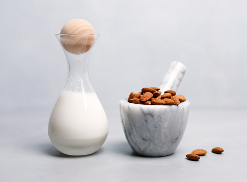 Almond milk in a glass jar with almond in a mortar