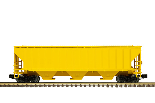A yellow railroad grain hopper freight car on track.