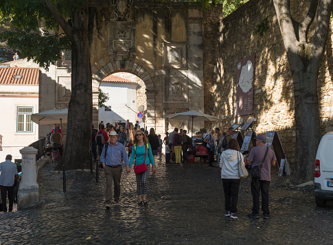 Lisbon, Portugal, October 24, 2021: View of Arco de Sao Jorge gate to medieval castel Castelo de sao Jorge at quarter Alfama, Lisabon with group of tourist people.