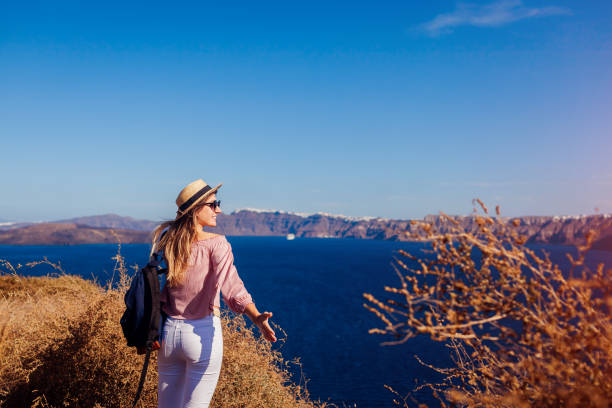 traveler woman walking on santorini island, greece enjoying landscape. happy hiker enjoys caldera view - caldera imagens e fotografias de stock