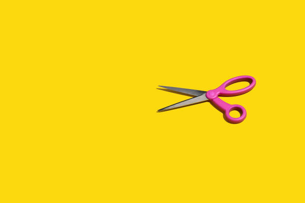 istock Pair of bright pink scissors on a yellow background 1460594543