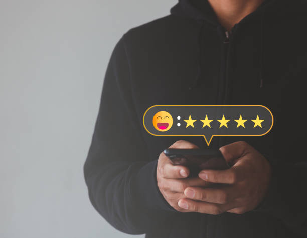 istock Customer service experience and business satisfaction survey. Close-up of man hand using smartphone with popup happy smile face, a five-star icon for feedback review satisfaction service. 1460596114