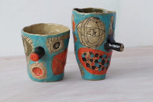 Colorful covered with glaze ceramic handmade mug. Isolated on a white background